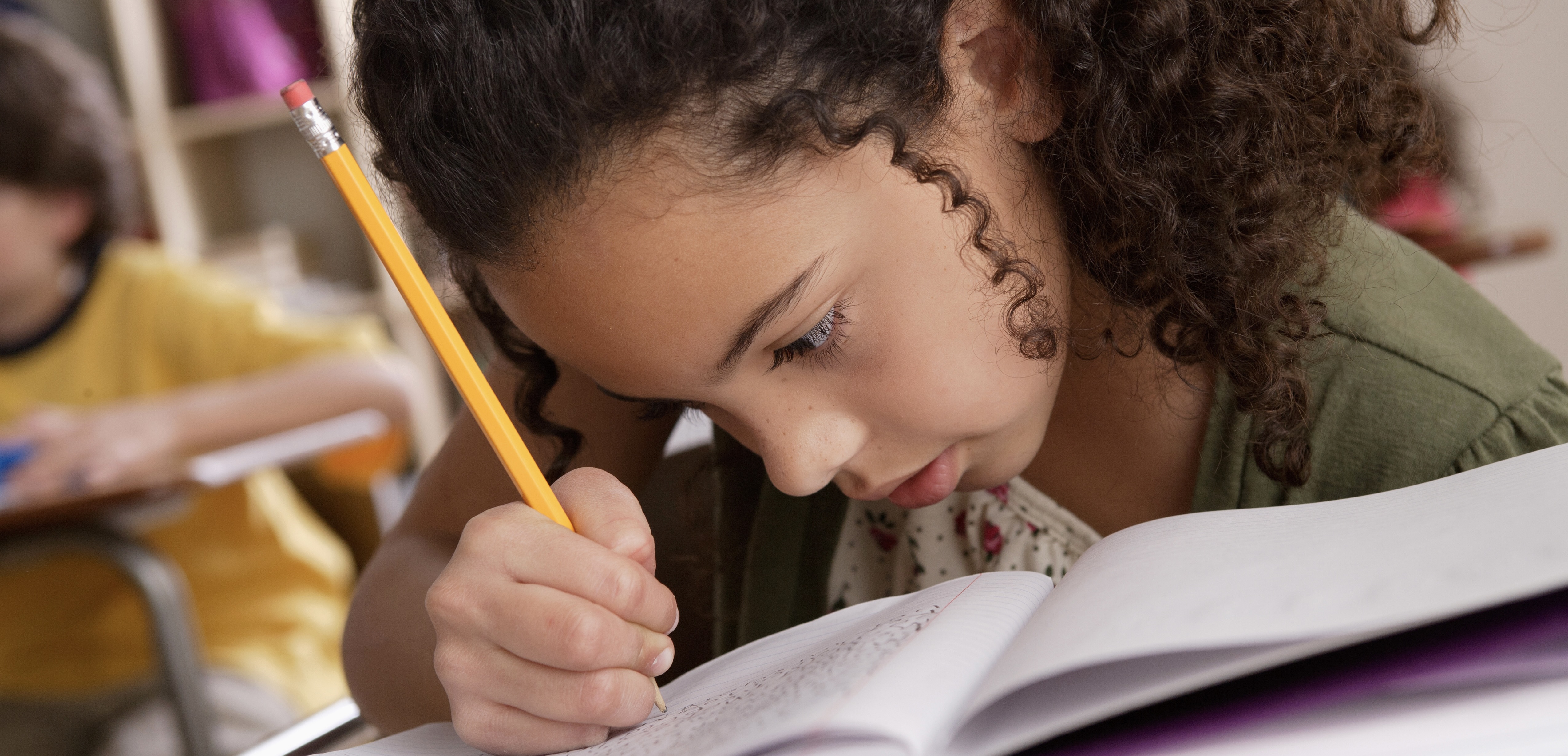 Photo d'une enfant écrivaznt en classe.