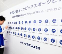 Un enfant regarde une affiche des pictogrammes des Jeux de Tokyo